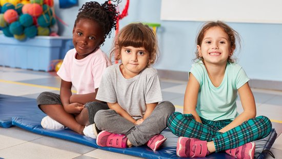 Kita-Kinder die auf einer Matte sitzen.